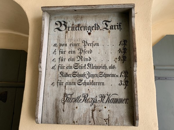 Hinweistafel mit altdeutscher Schrift: Brückengeld Tarif - a) von einer Person 1Pf. b) für ein Pferd 4 Pf. c) für ein Rind 4 Pf. d) für ein Kleinvieh als Kälber, Schafe, Ziegen, Schweine 1 Pf. e) für ein Schubkarren 3 Pf. - Fürstl. Reys Pl. Kammer