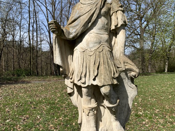 Statue eines Mannes im Park. Die Statue hat leichte grünbraune Altersflecken.